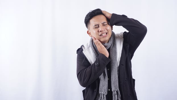 Sick Young Asian Man with Swollen Cheek Suffering from Toothache on White Background photo