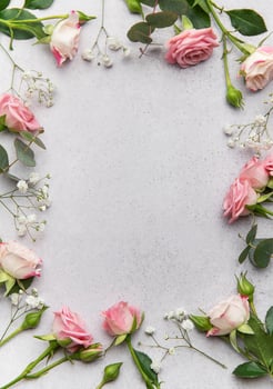 Pink roses and eucalyptus leaves creating a frame on a gray background photo