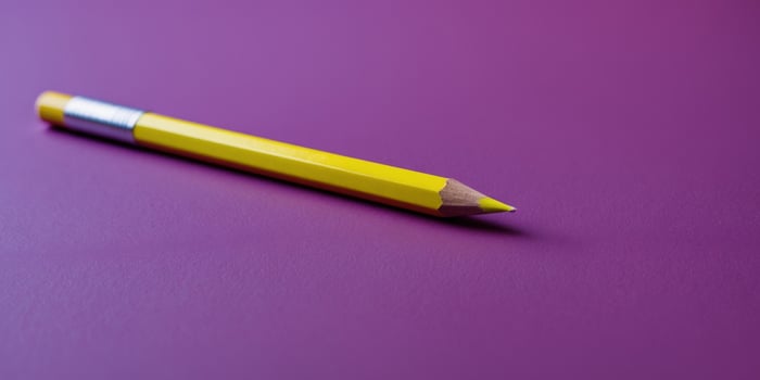 Bright Yellow Pencil Pointing on Vibrant Purple Background photo