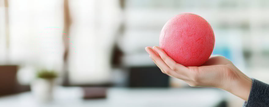A hand holding a textured red ball in a bright indoor setting. Stress, anxiety and overwhelmed for deadline frustrated tired concept. photo