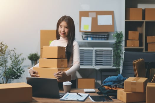 A woman is holding a stack of boxes in her office photo