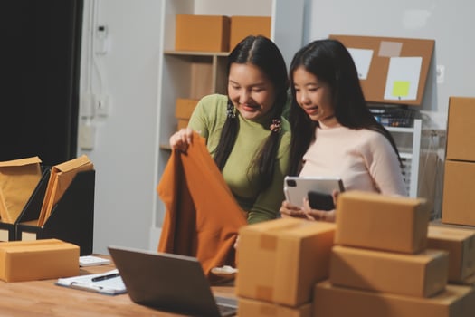 Two women in an office looking at a laptop and boxes photo
