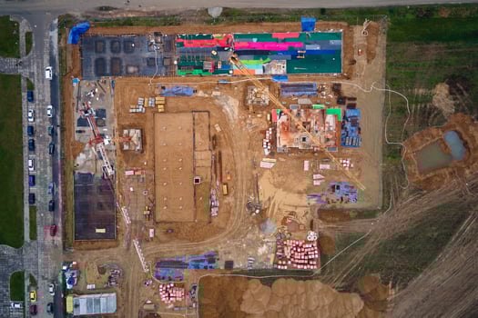Aerial view of construction site with cranes, foundations and building materials. Residential building under construction. Progress of new development in small town photo