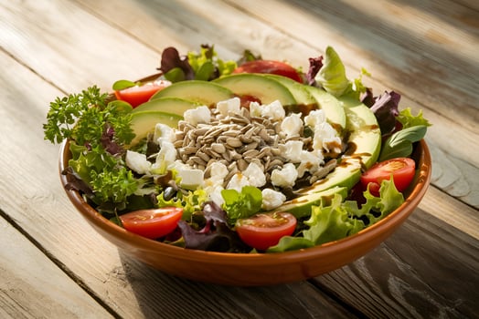 Delicious Healthy Avocado Salad with Feta and Sunflower Seeds on Wooden Table photo