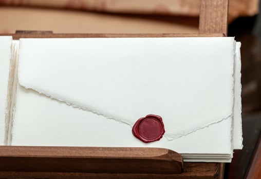 Stack of handmade paper invitations with red sealing wax in wooden box photo