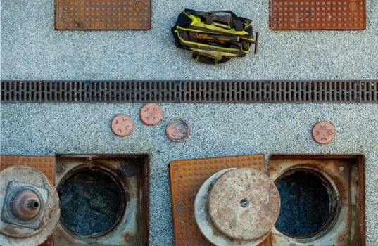Plumber bag and tools laying near open manholes and drainage channel photo