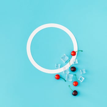 Trendy summer composition made of red cherries and ice cubes on light blue background with copy space. Flat lay summertime drink minimal concept. Cherry fruit aesthetic. Top view banner. photo