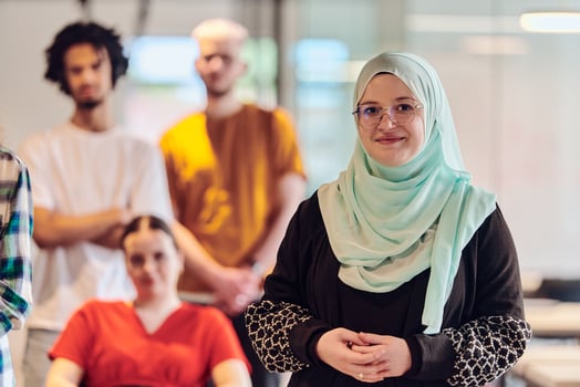 A diverse group of young business people congregates within a modern startup's glass-enclosed office, featuring inclusivity with a person in a wheelchair, an African American young man , and a hijab photo