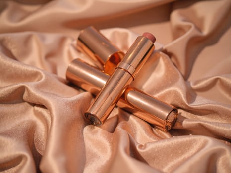 A lipstick and a lipstick tube laying on a satin cloth photo