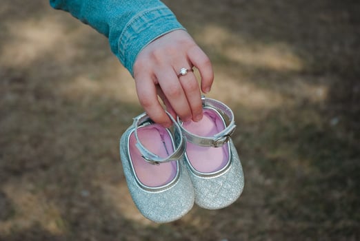 Child's silver shoes with hand in nature setting for family announcement or celebration design. Pregnancy, expecting a child. Single mother photo