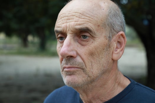 Serious Elderly Bald Man Looks Around Seated in Nature Park photo