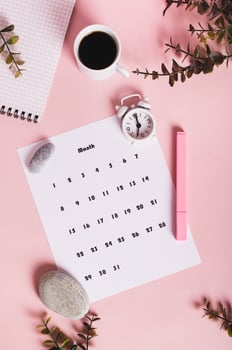 Calendar, alarm clock, notebook and pen on a pink background top and vertical view photo