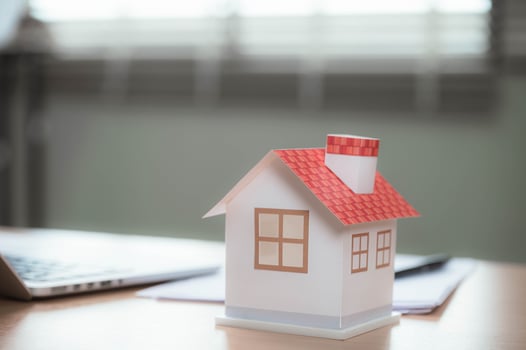 Concept of real estate investment planning with house model on desk near laptop and financial documents, representing home mortgage preparation and housing market strategy for buyers photo