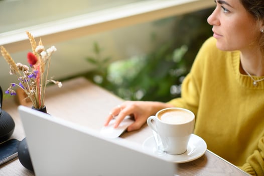 A young woman enjoys her freelance work at a cozy cafe, typing on her laptop with a cup of coffee in hand. photo