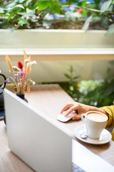 A freelancer enjoys the cafe atmosphere, holding a coffee cup while brainstorming ideas on her laptop. photo