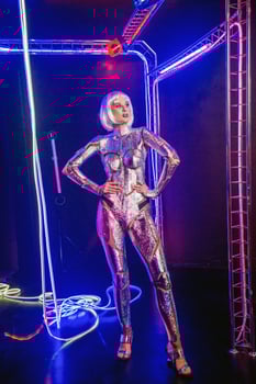 cyber girl in shining silver armor in neon. blonde with fantastic makeup and image in dark key and colored light. fashion model posing in cyber space. she as a creative robot photo