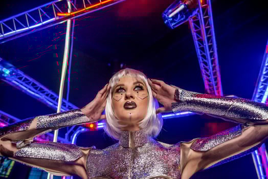 close-up of blonde girl as cyber robot. girl in shining silver armor in neon. blonde with fantastic makeup and image in dark key and colored light. fashion model posing in cyber space photo