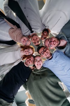 In a modern office, a group of young business professionals is captured in a warm and embracing hug, reflecting the spirit of unity, collaboration, and shared success in their dynamic workplace. photo