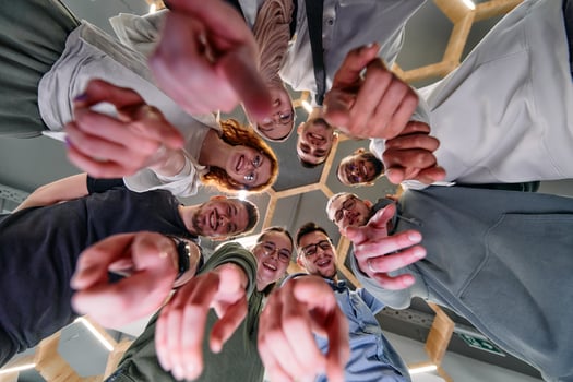 A group of cheerful young people gathered in a circle, pointing at the camera from a low-angle perspective. photo