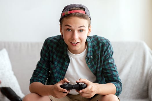 Excited teenager playing games at home, eating unhealthy food, enjoying his free time photo