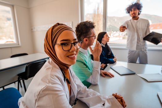 A medical team discussing at a meeting in the office a muslim female doctor in hijab smiling looking at camera. photo
