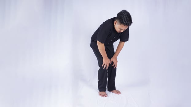 Young Asian Man Suffering from Knee Pain on White Background photo