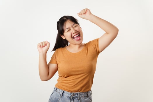 A young woman in casual clothes raising her arms, smiling, laughing with joy, cheerful emotion. photo