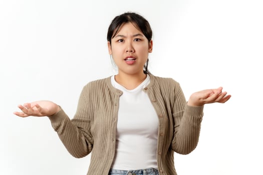 A confused and curious young woman in casual clothes spreads her arms out in a curious manner. photo