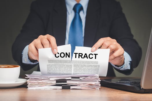 Businessman in a suit tearing up a contract while sitting at the table photo