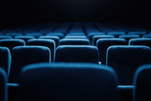 Rows of plush seating, bathed in a cool blue tone, await a captivated audience in the darkness photo