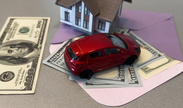 property, real estate, financial, loan, wealth, investment, construction, estate, insurance, residential. A car is on a table next to a house. The car is a toy and the house is a model. photo
