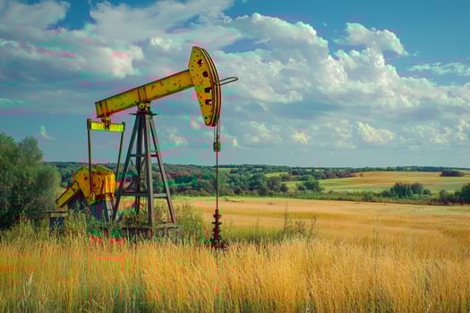 Oil pump jack operating in golden wheat field landscape photo