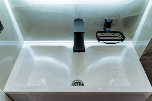 The elegantly designed bathroom boasts a contemporary sink accompanied by a chic black faucet and a coordinating soap dish, all combining to establish a sophisticated, modern aesthetic photo