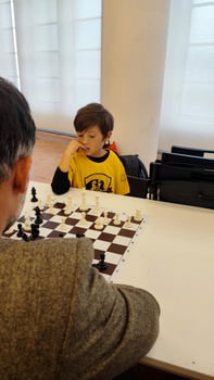 Clever junior school age boy playing chess with dad planning gambit moving black piece on chessboard. Preteen son engaged in brain developing activity enjoy board game with father photo