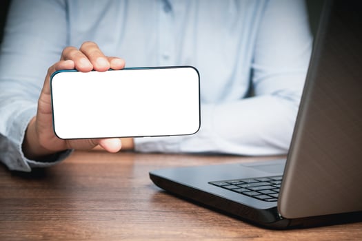 Close-up of hand holding a horizontal mobile phone with a blank white screen photo