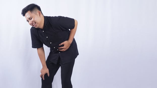 Asian Man Touching on His Stomach Suffering from Abdominal Pain on White Background photo