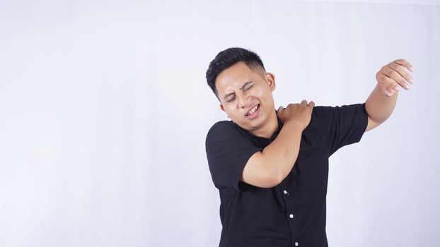 Asian Man Feels Pain in His Shoulder on White Background photo