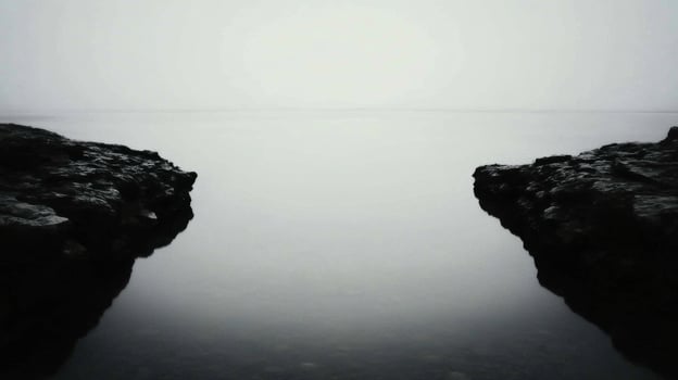 Calm waters reflect gray sky at a rocky coastal location photo