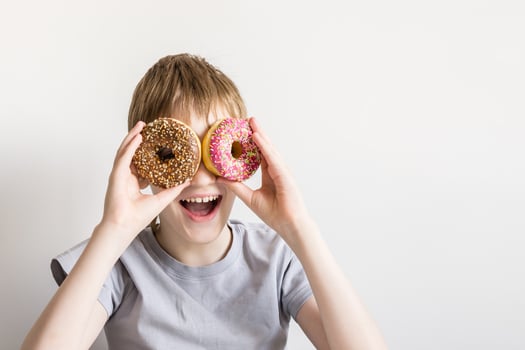 Teen boy looks into donut holes and smiles fun photo