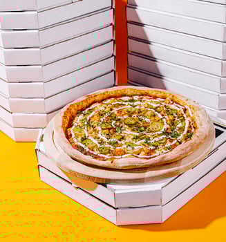 Freshly baked pizza surrounded by empty pizza boxes on orange photo