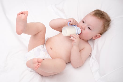 Sweet little baby drinking milk in a plastic bottle relaxing. photo