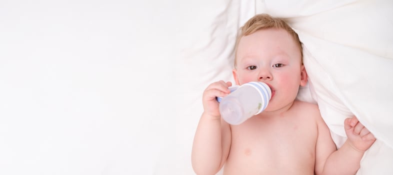 Sweet little baby drinking milk in a plastic bottle relaxing photo