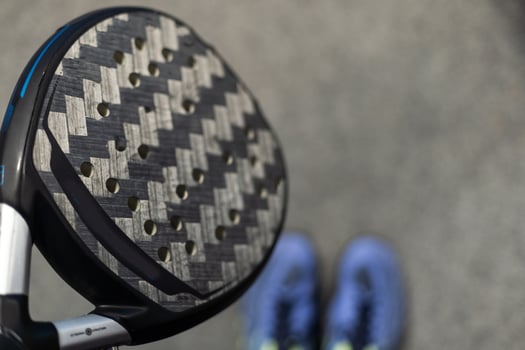 Closeup view of a paddle racket in a padel tennis court near the net. Sport, health, youth and leisure concept. Sporty equipment. White lines in background photo