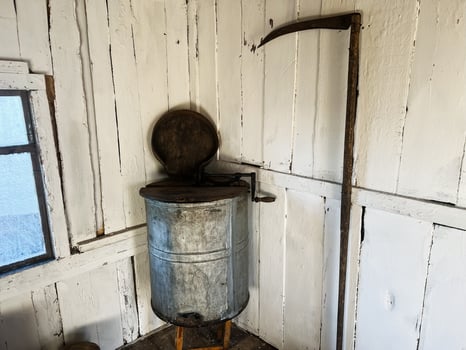 Vintage rustic tools displayed in an antique farmhouse interior next to a window photo