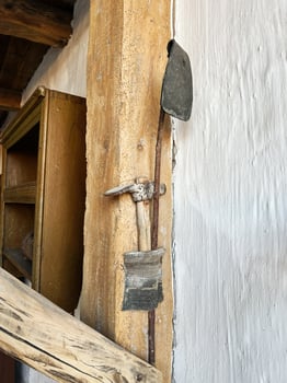 Rustic hand tools displayed on rough wooden supports in a historical setting photo