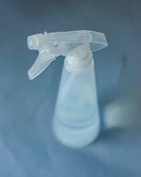 Clear plastic spray bottle filled with water,isolated against neutral background. High quality photo