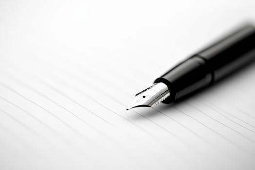 Close-up of a fountain pen poised above blank paper, ready for writing in a creative workspace photo