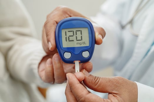 Asian doctor using digital glucose meter for check sample blood sugar level to treatment di photo