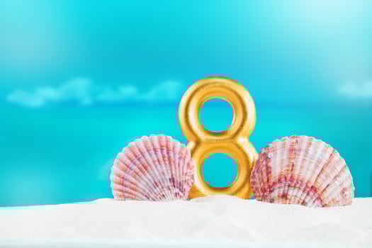 golden number 8 stands on soft sand, by large pink seashells, against backdrop of calm blue sea on sunny day. Celebration, nature, International Women's Day, birthday, hot country, summer vacations photo