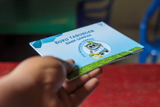 Hand Holding Waste Bank Savings Book for Recycling Awareness, Bandung - Indonesia, 15 February 2025 photo